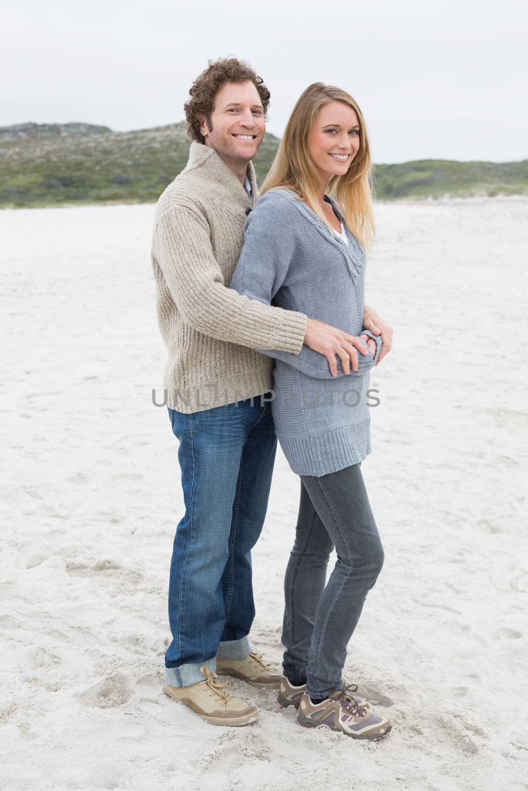 Full length portrait of a relaxed romantic young couple standing together at the beach