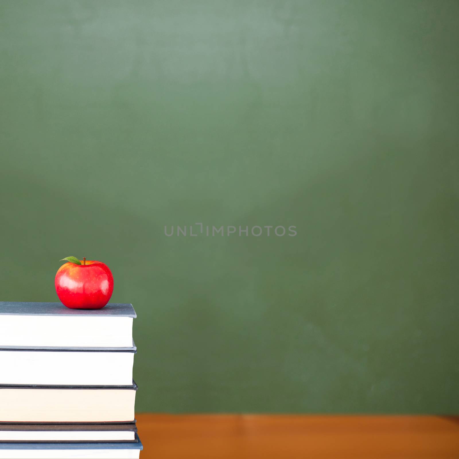 Red apple on pile of books in classroom by Wavebreakmedia