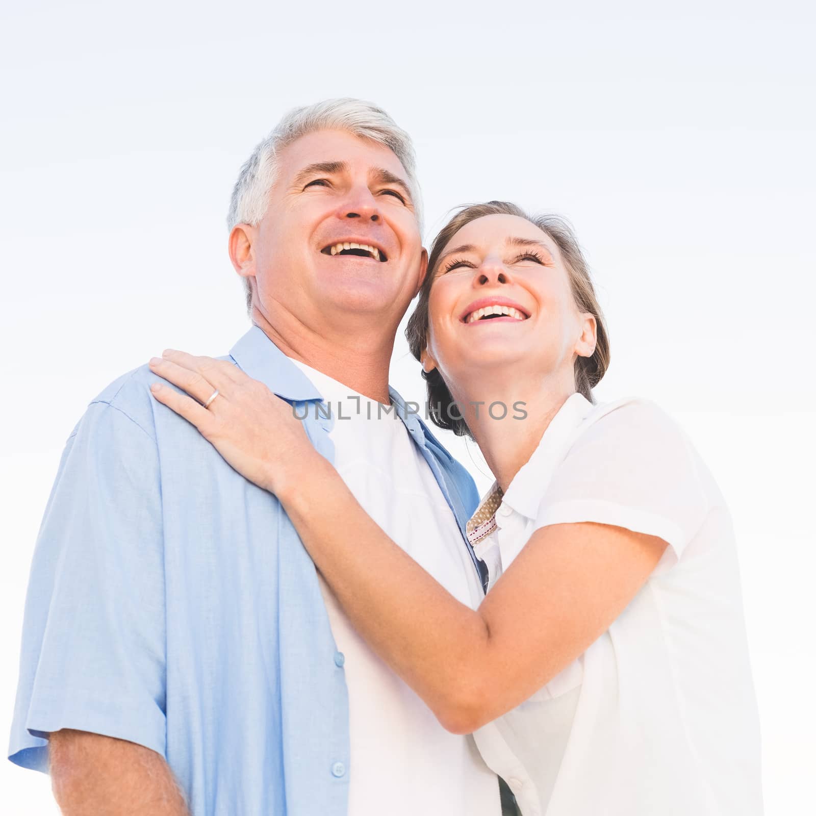 Happy casual couple embracing under blue sky on a sunny day