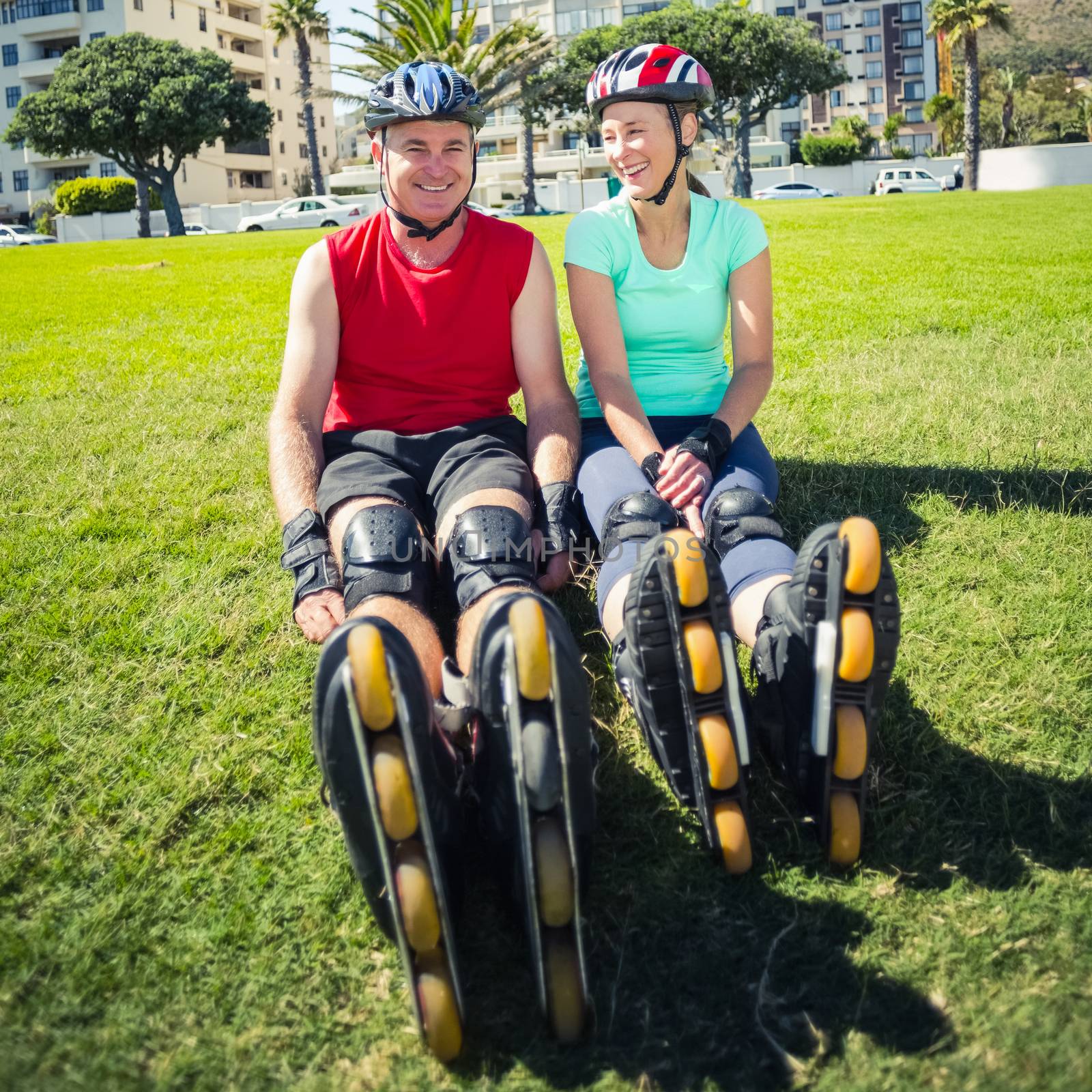 Fit mature couple wearing roller blades on the grass on a sunny day