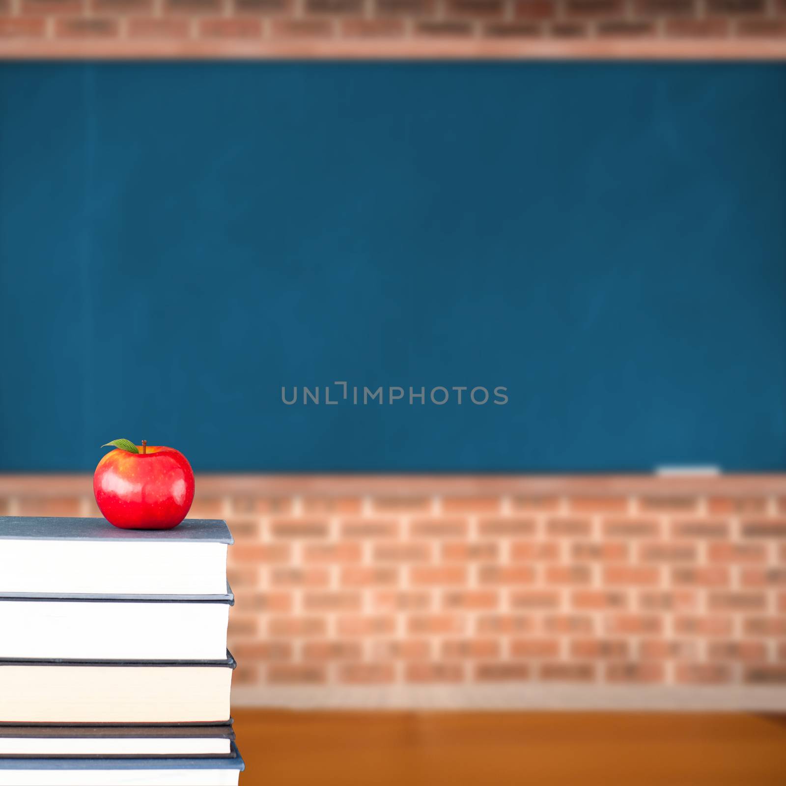 Red apple on pile of books in classroom in copy space