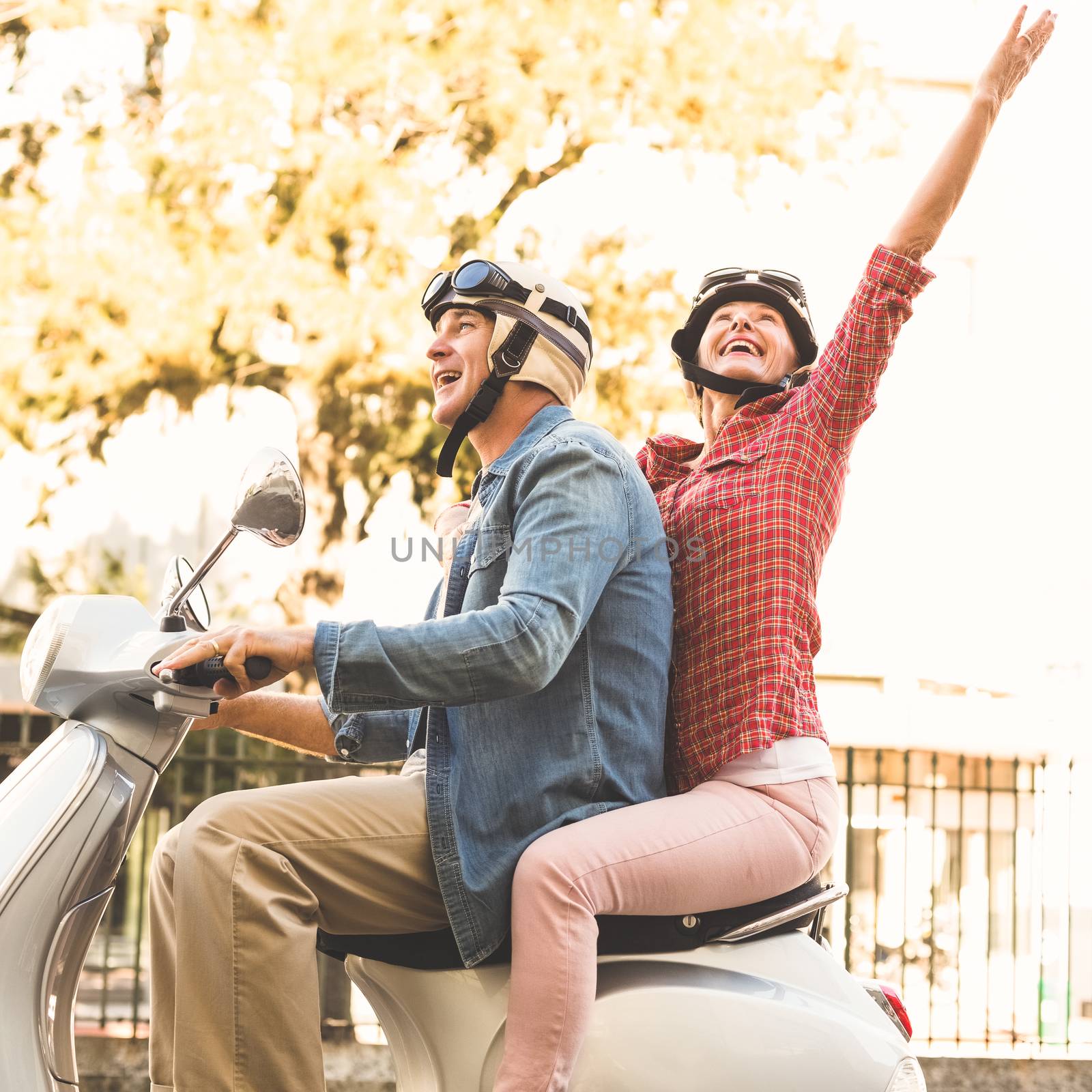 Happy mature couple riding a scooter in the city by Wavebreakmedia