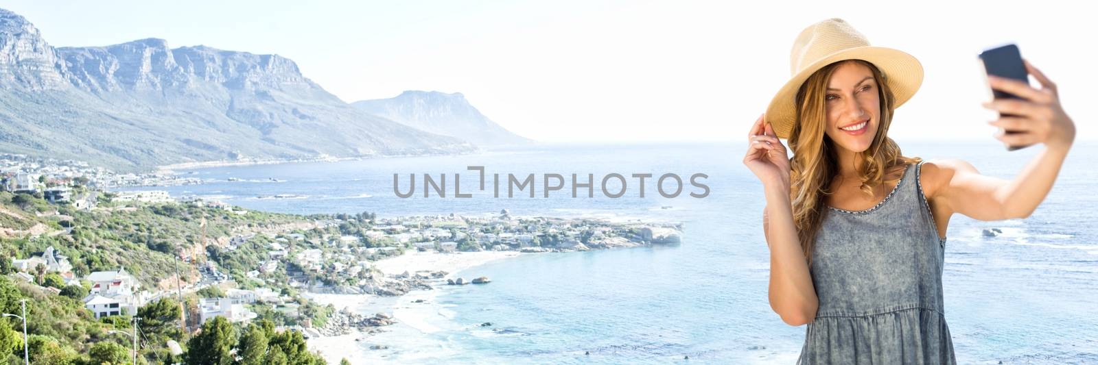 Digital composite of Millennial woman in summer clothes taking selfie against blurry coastline