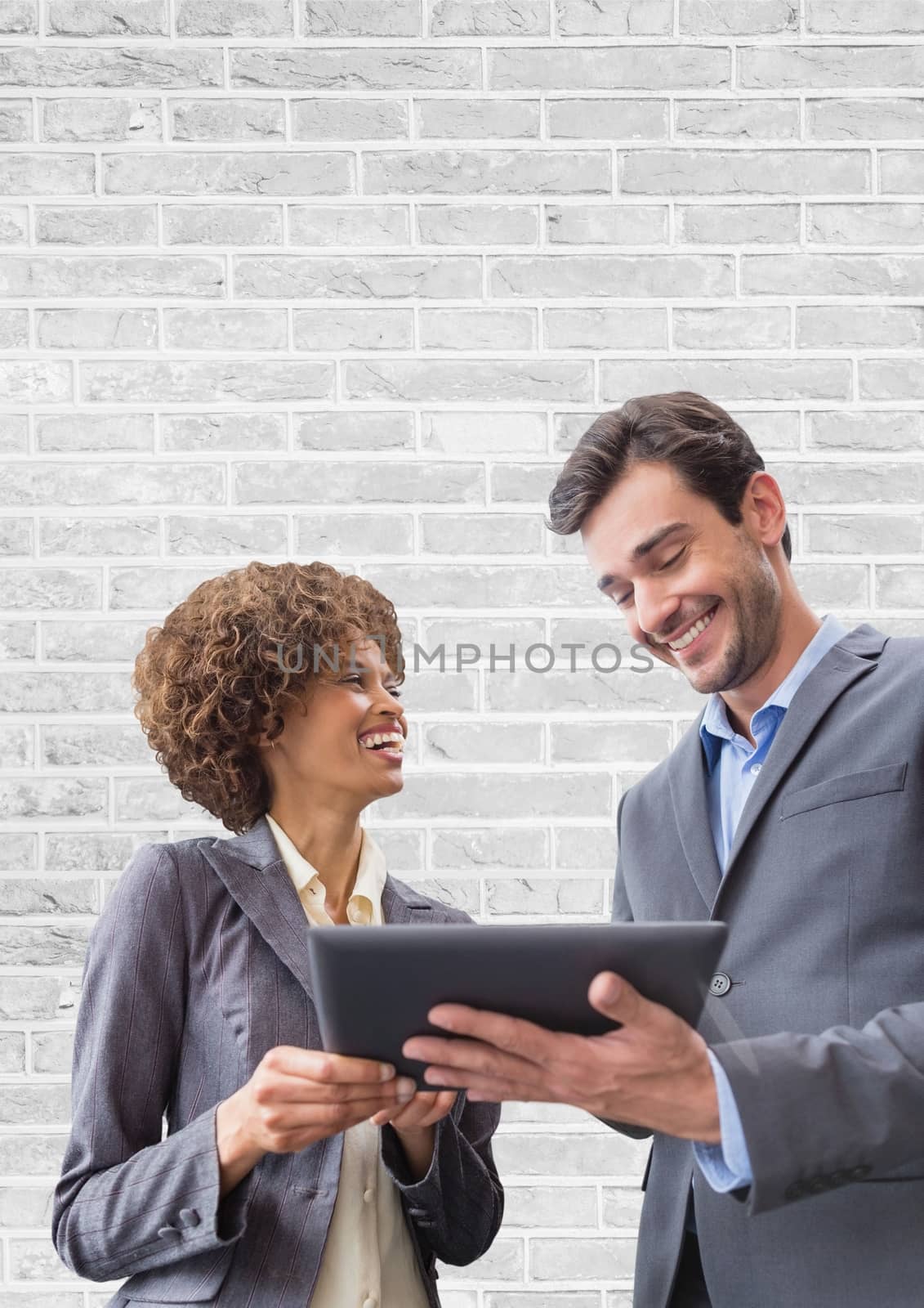 Digital composite of Happy business people using a tablet against white wall