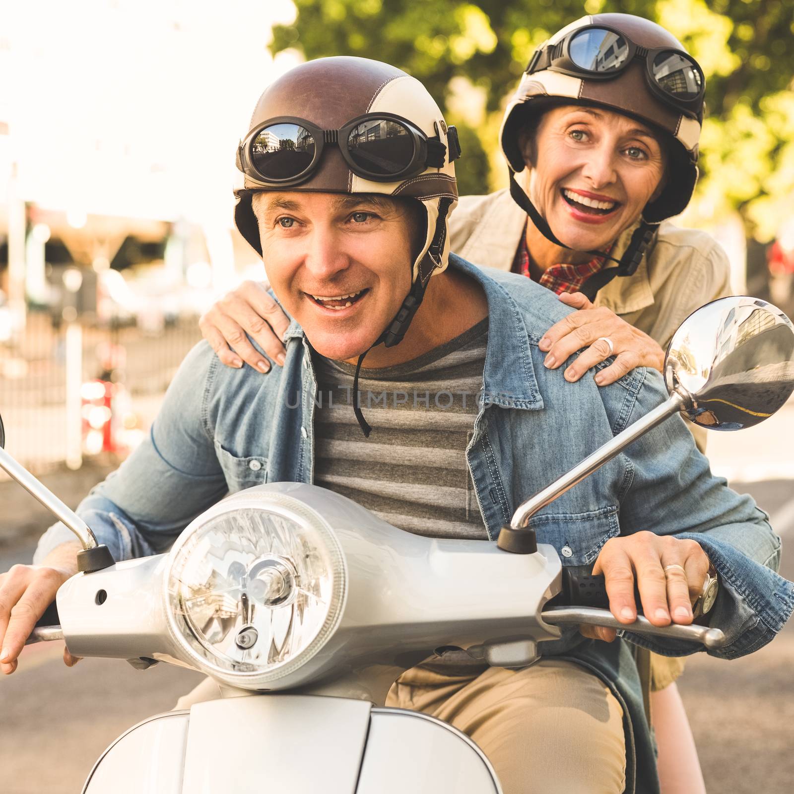 Happy mature couple riding a scooter in the city by Wavebreakmedia