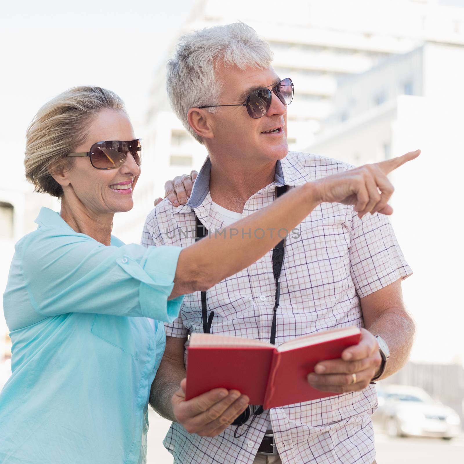 Happy tourist couple using tour guide book in the city by Wavebreakmedia