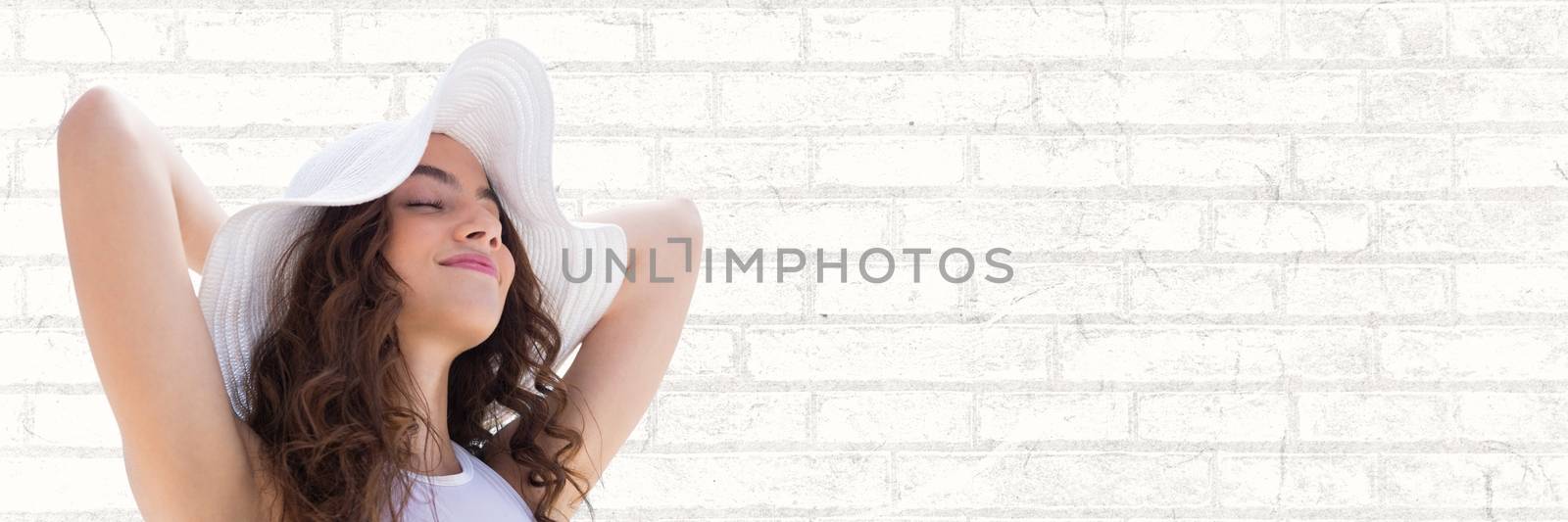 Digital composite of Portraiture of woman in summer hat relaxing against white brick wall