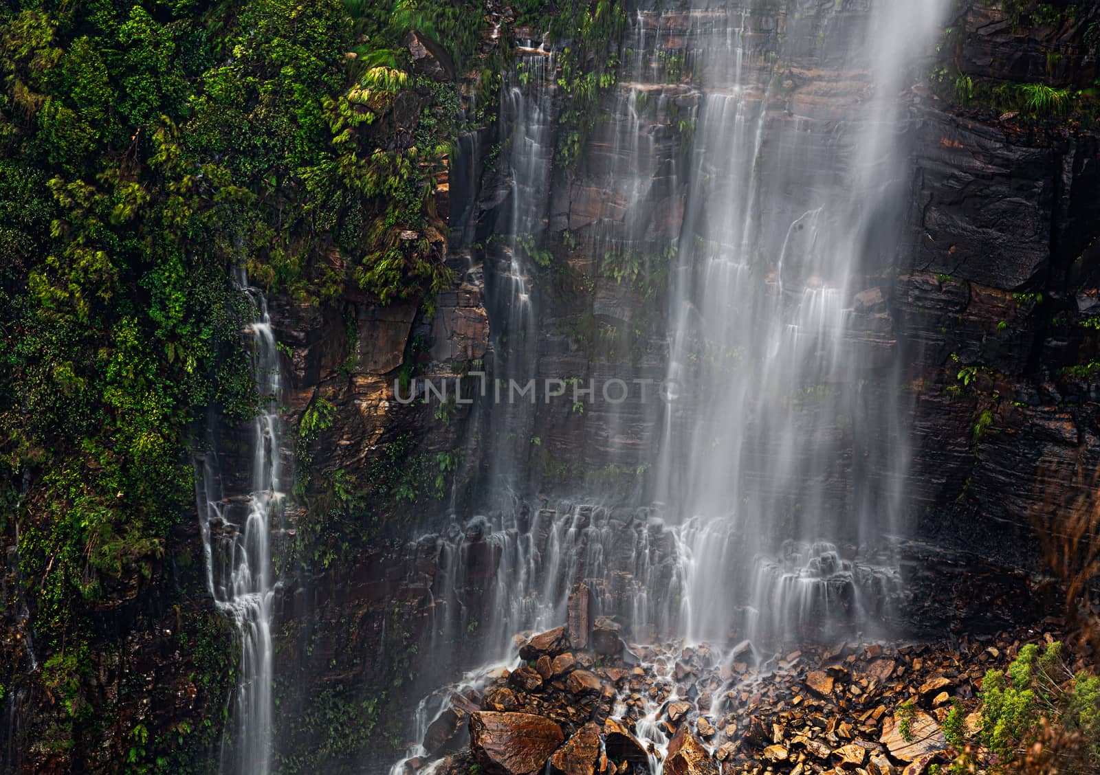 Waterfall cascading onto a rocky rubble at its cliff base by lovleah