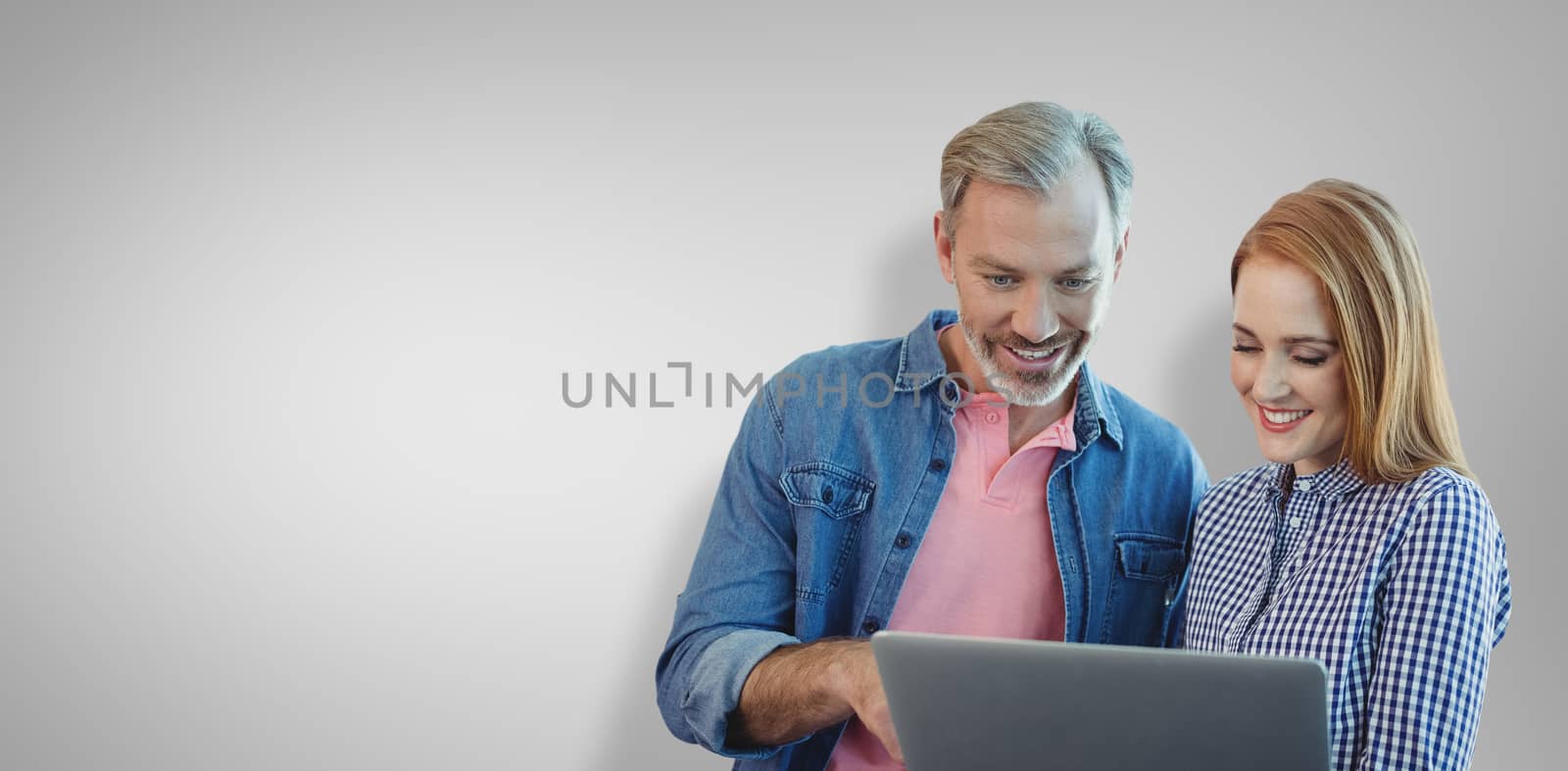 Portrait of smiling business people using laptop against grey vignette