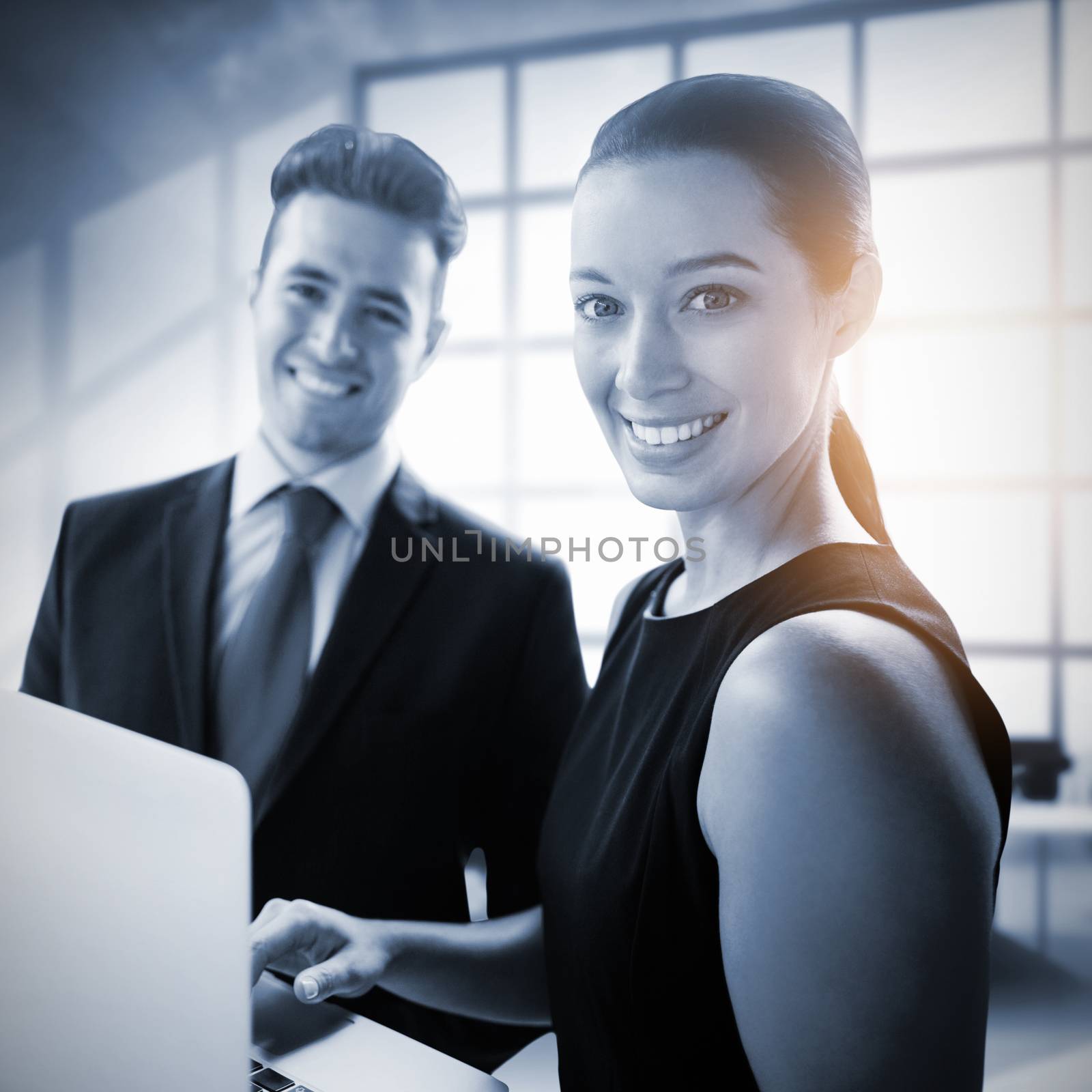 Business people standing with a laptop against interior of empty office