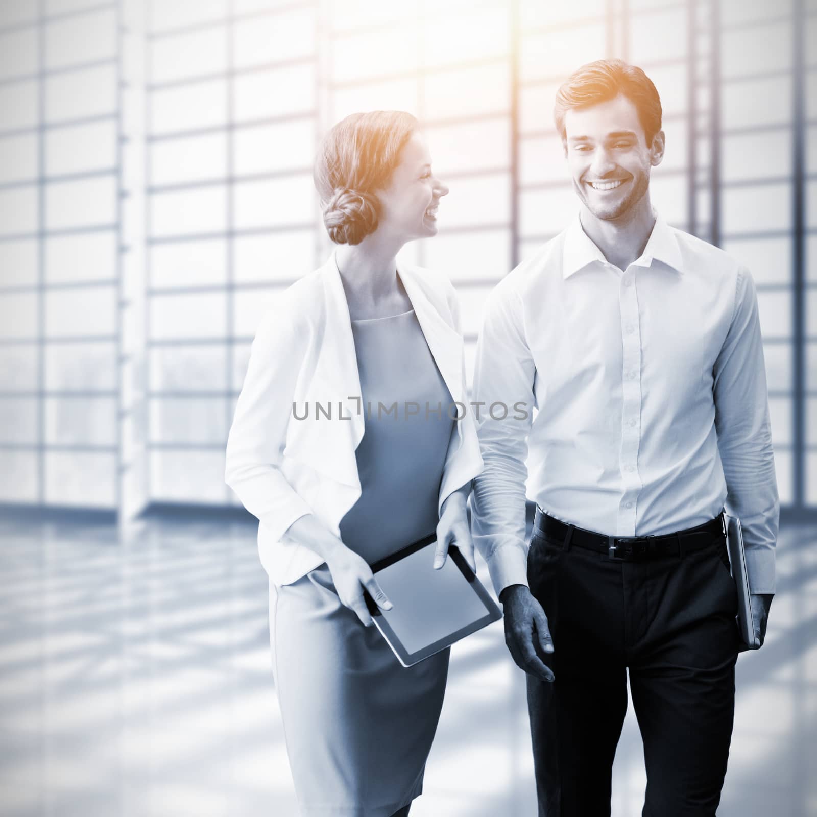 Business colleagues using digital tablet while walking  against white room with large window overlooking city