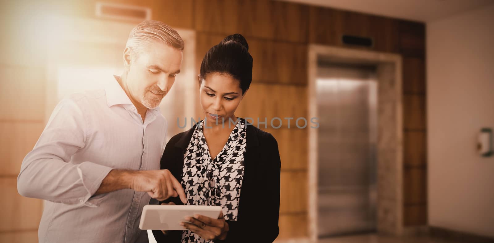 Portrait of business people using digital tablet  against closed lifts in modern office