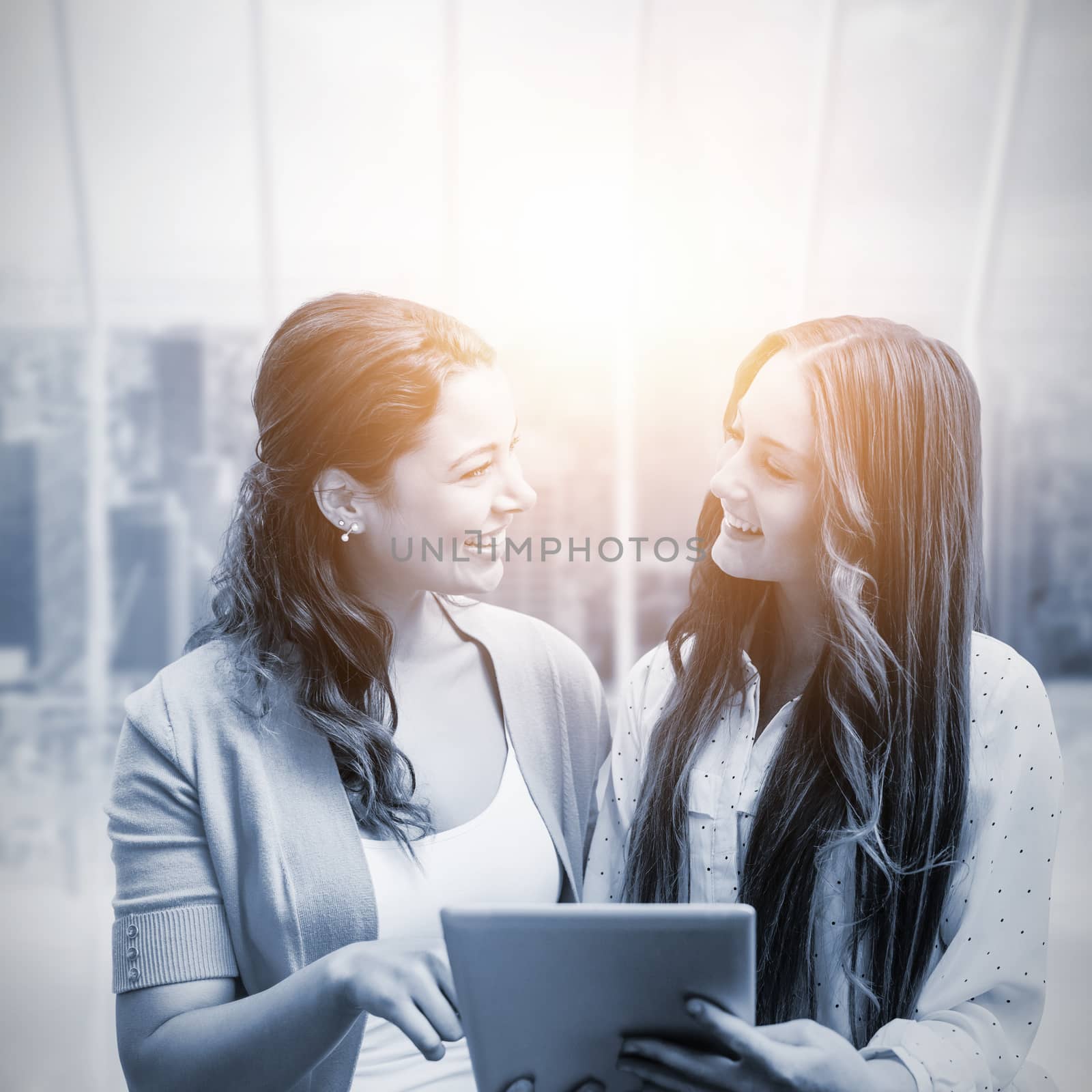 Smiling girls holding tablet against room with large window looking on city