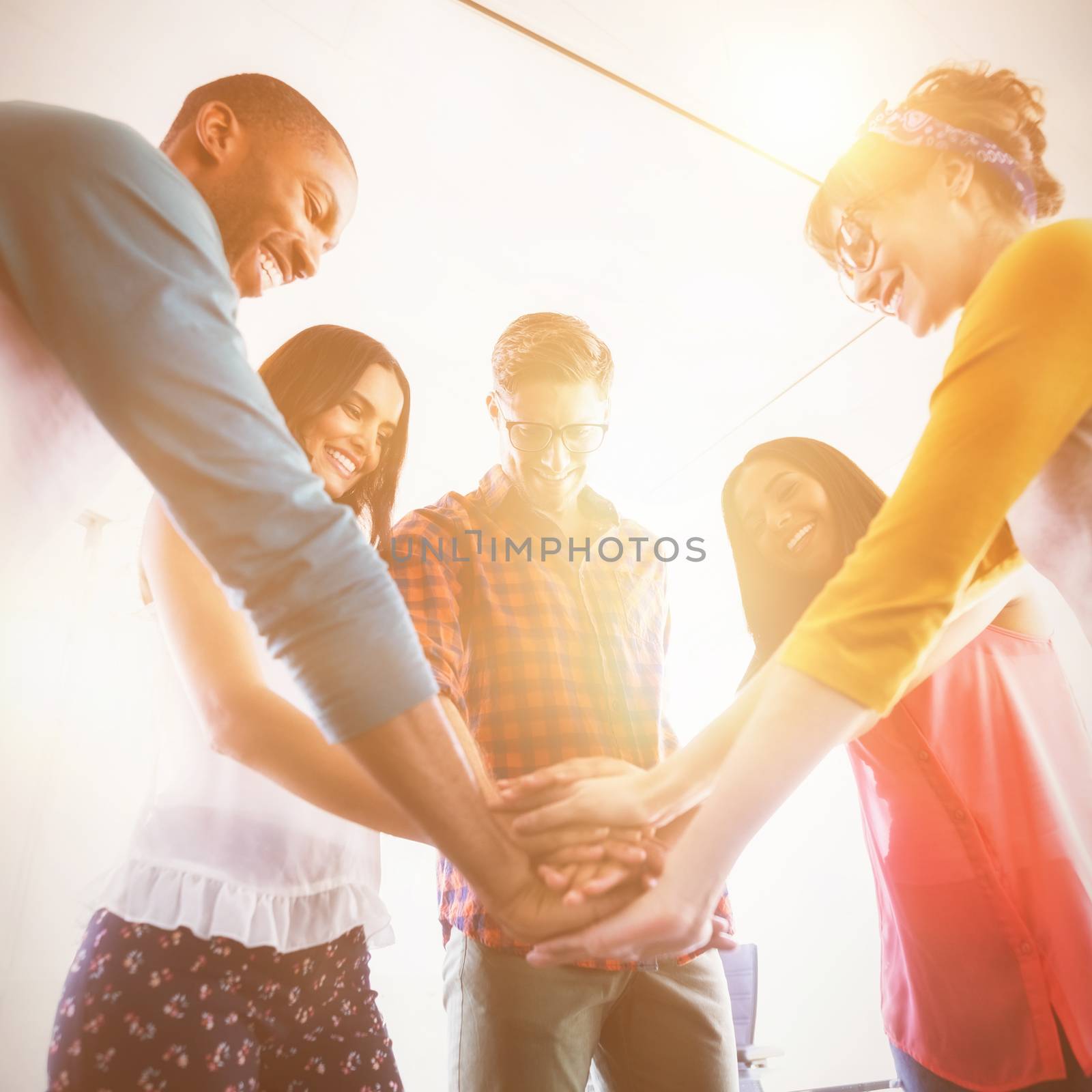 Low angle view of business people stacking hands while standing in office