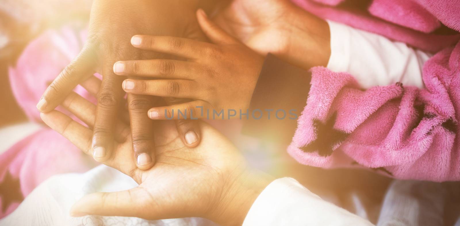 Family forming hand stack while playing on bed in bedroom