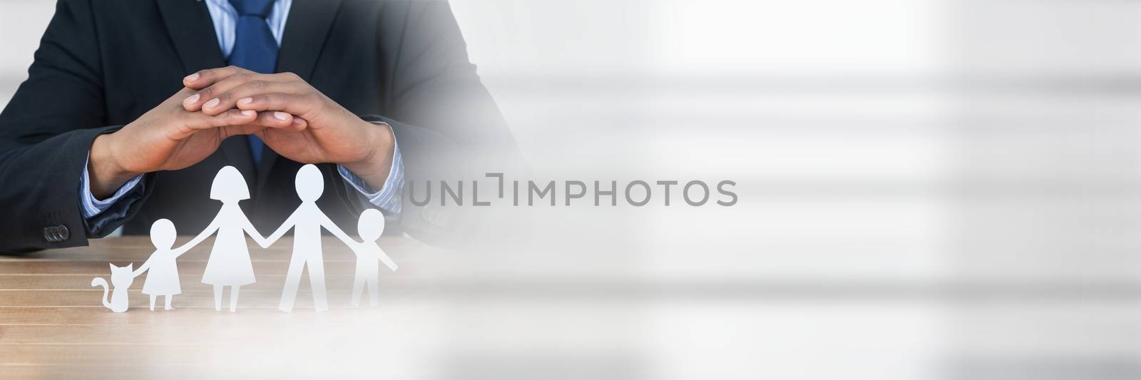 Man standing behind a table with paper figures as family insurance concept by Wavebreakmedia