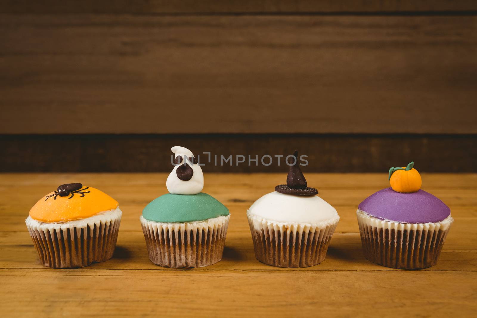 Colorful cup cakes arranged on wooden table during Halloween