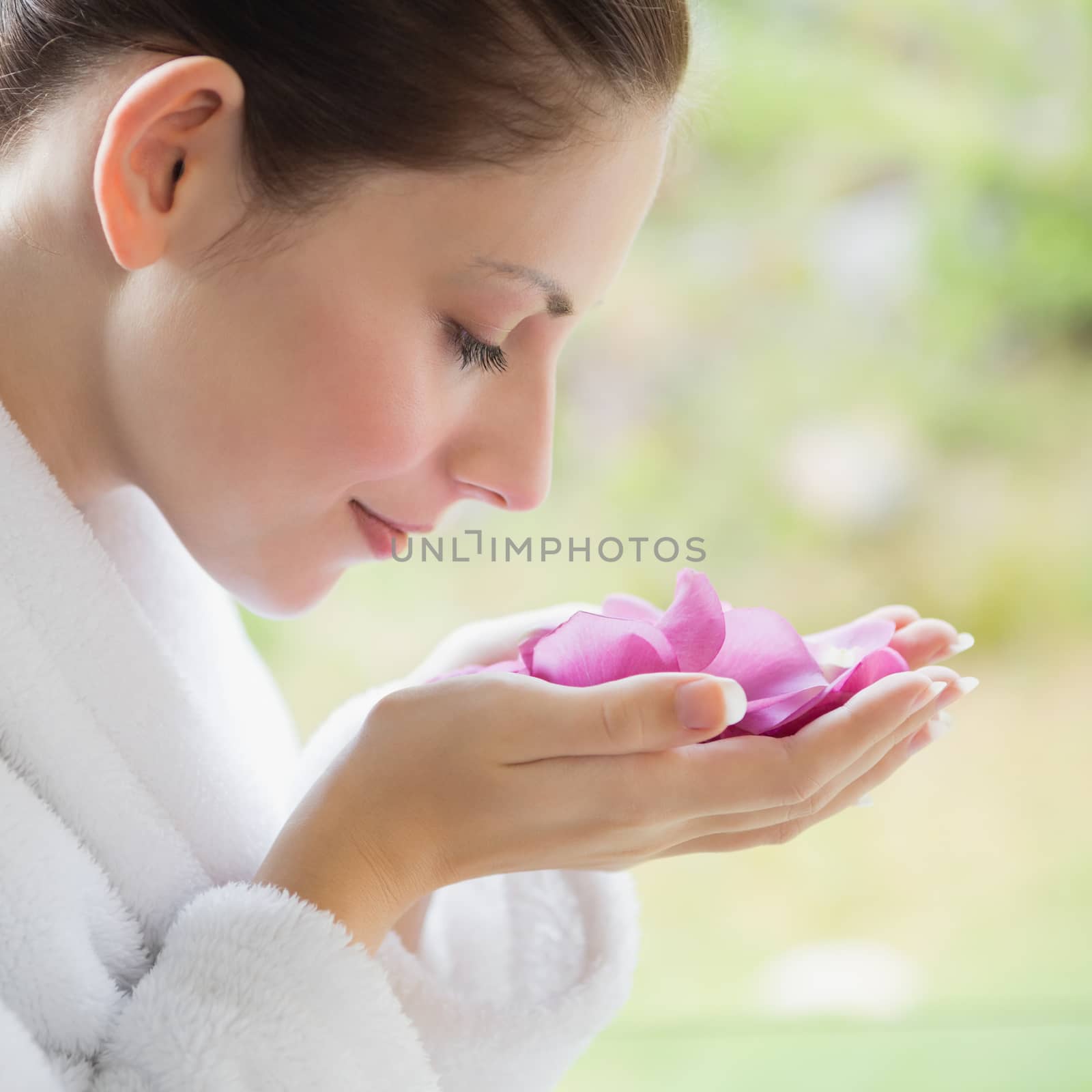 Close up side view of beautiful young woman smelling flowers in spa