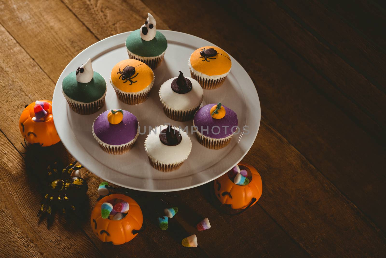 High angle view of cup cakes with decorations on wooden table during Halloween