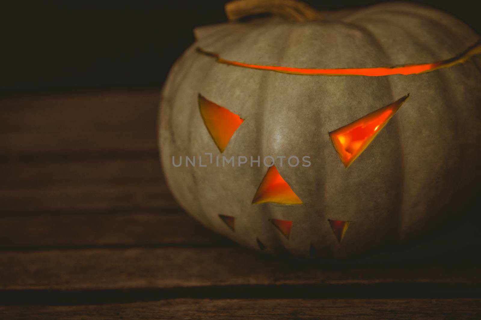 Close up of illuminated white jack o lantern on table during Halloween