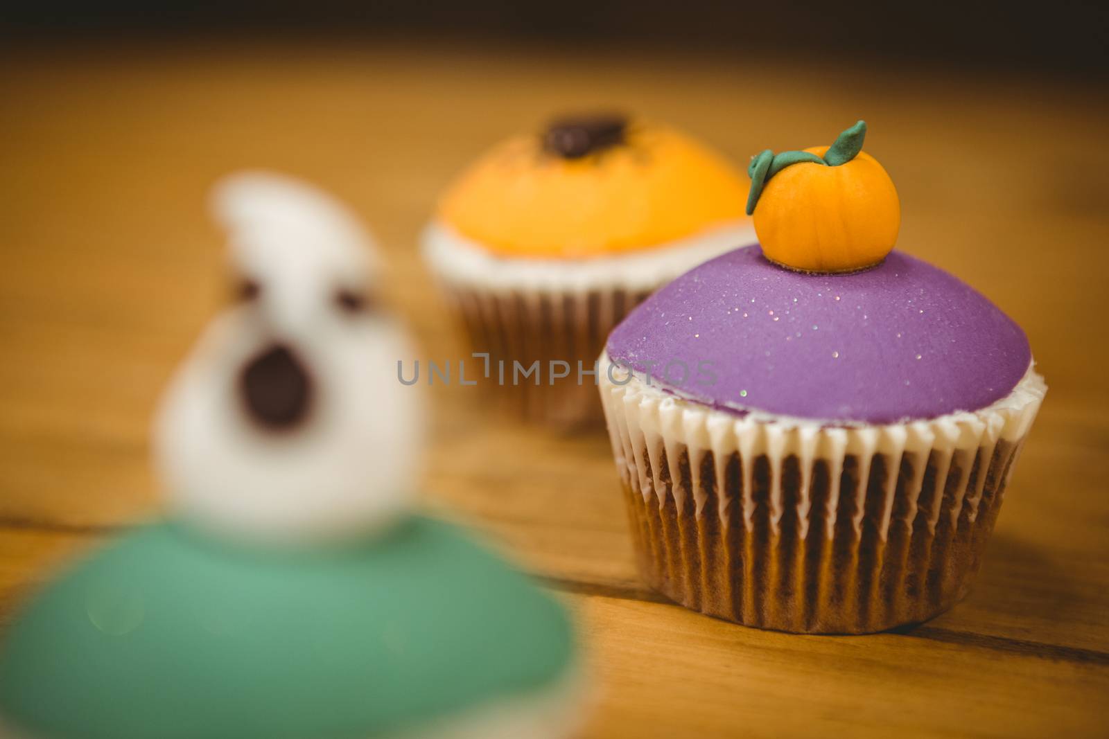 Close up of cup cake with pumpkin on wooden table during Halloween