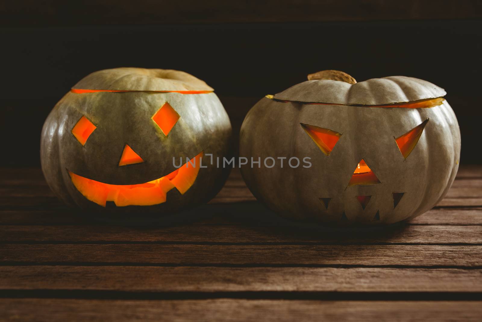 Close up of illuminated jack o lanterns on table during Halloween by Wavebreakmedia