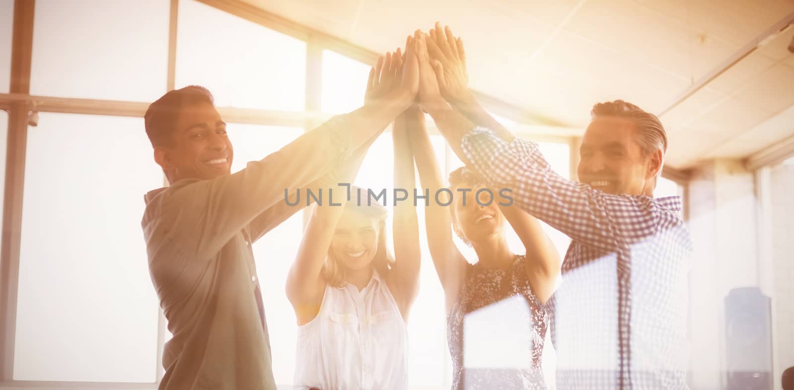 Portrait of business people raising hands seen through glass at creative office