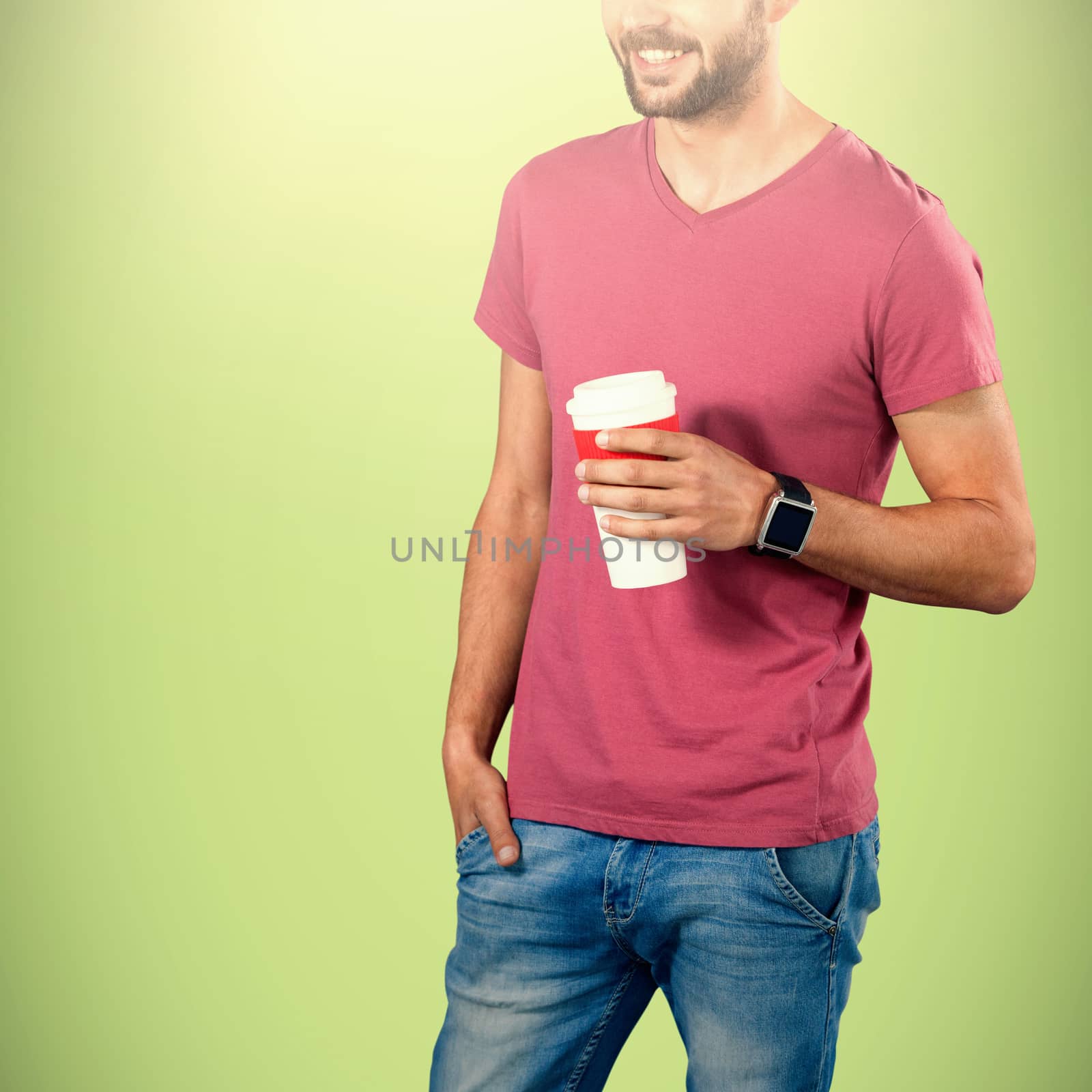 Midsection of smiling model holding disposable coffee cup against green background