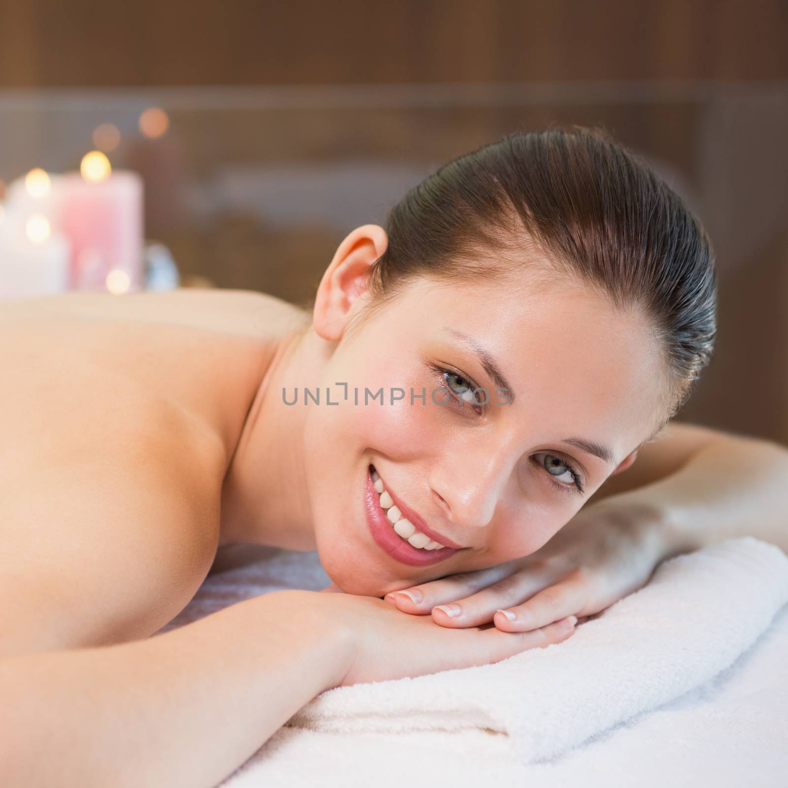 Close up portrait of a beautiful young woman lying on massage table at spa center