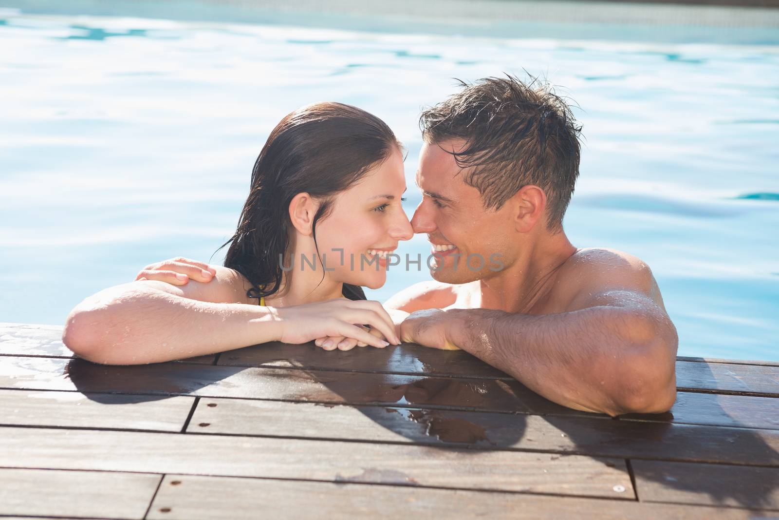 Smiling romantic young couple in swimming pool on a sunny day