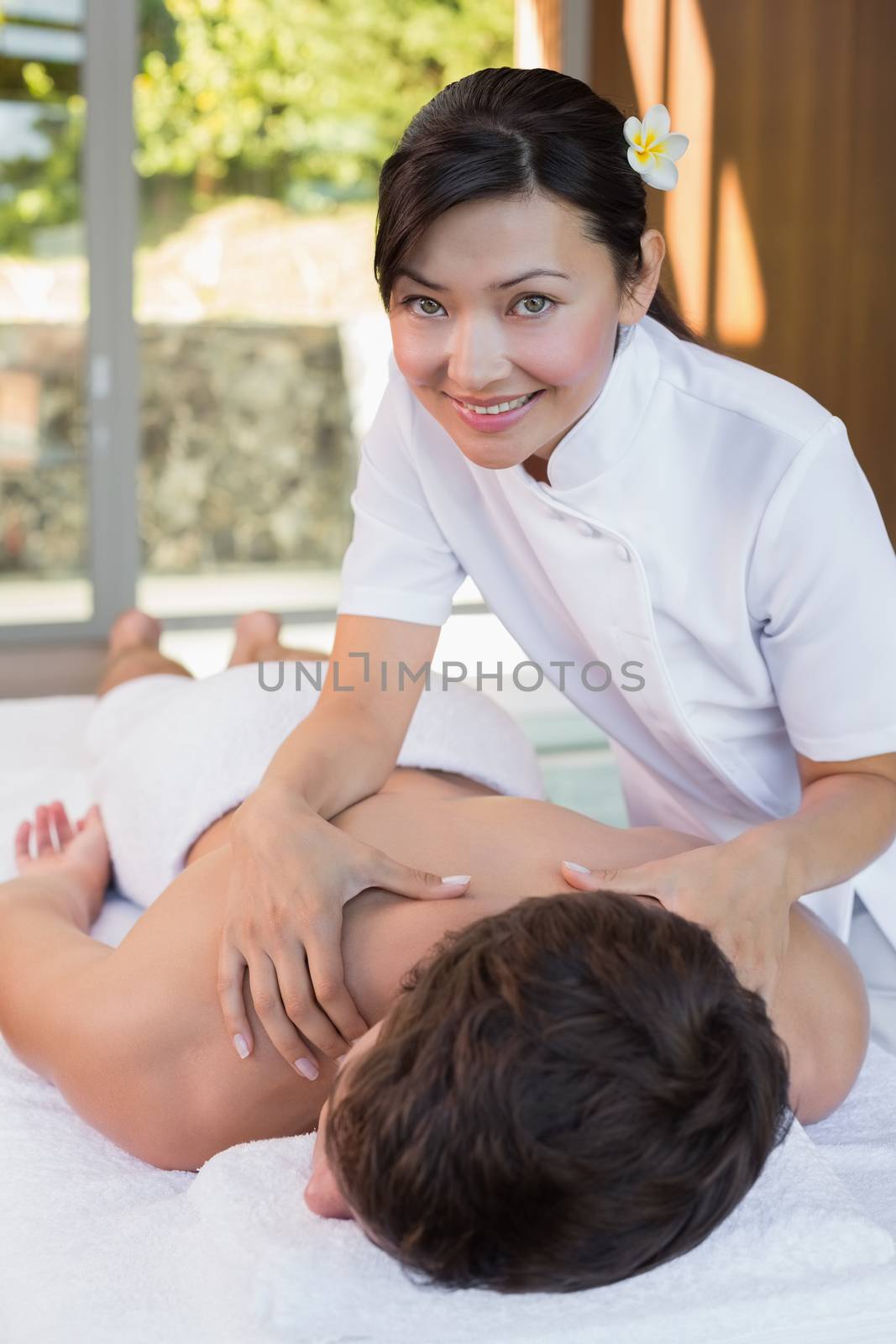 Portrait of a female masseur massaging mans back at spa center