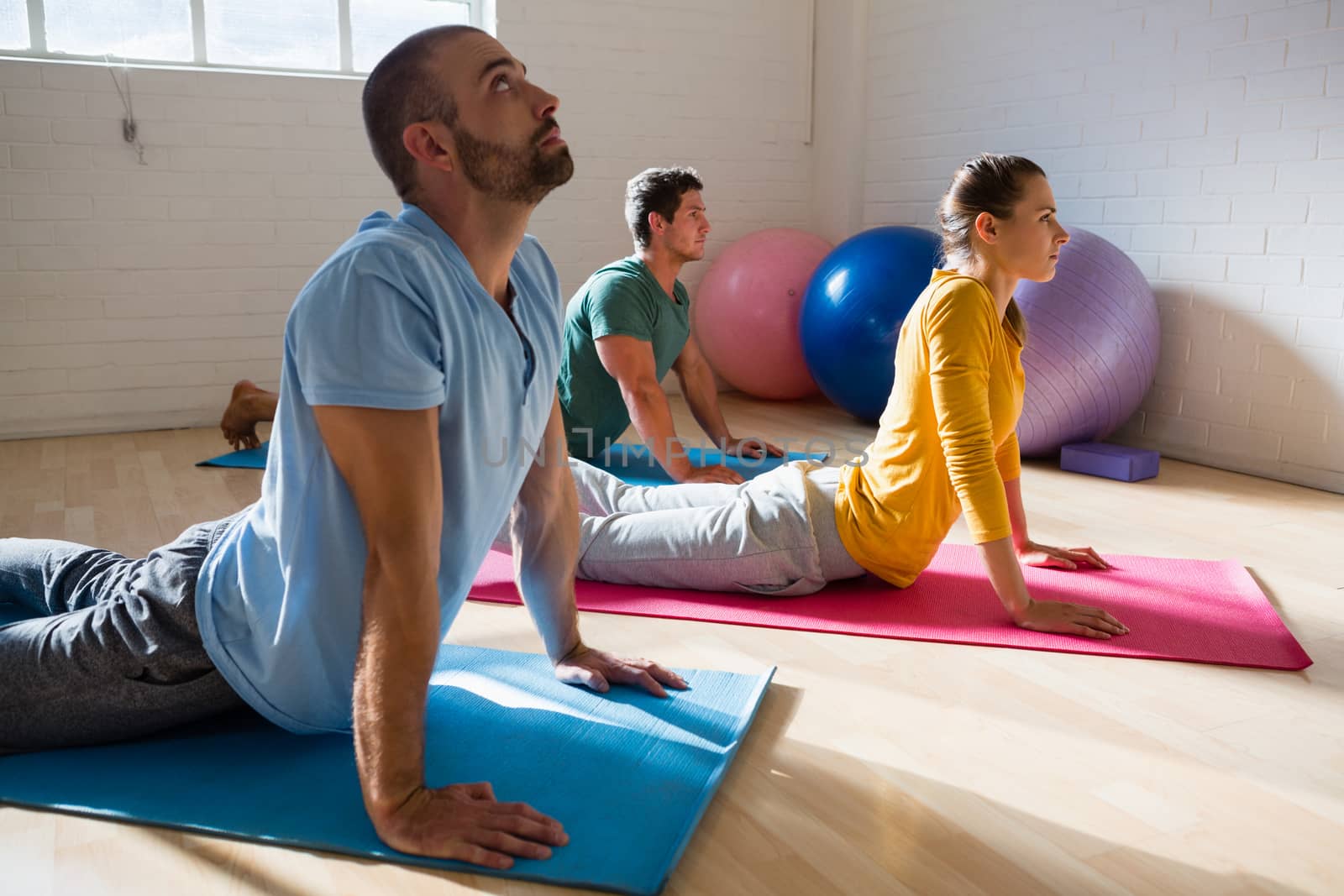 Yoga instructor training students in practicing cobra pose at health club