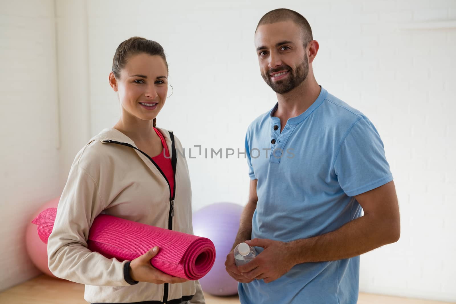 Portrait of student with instructor standing in yoga studio