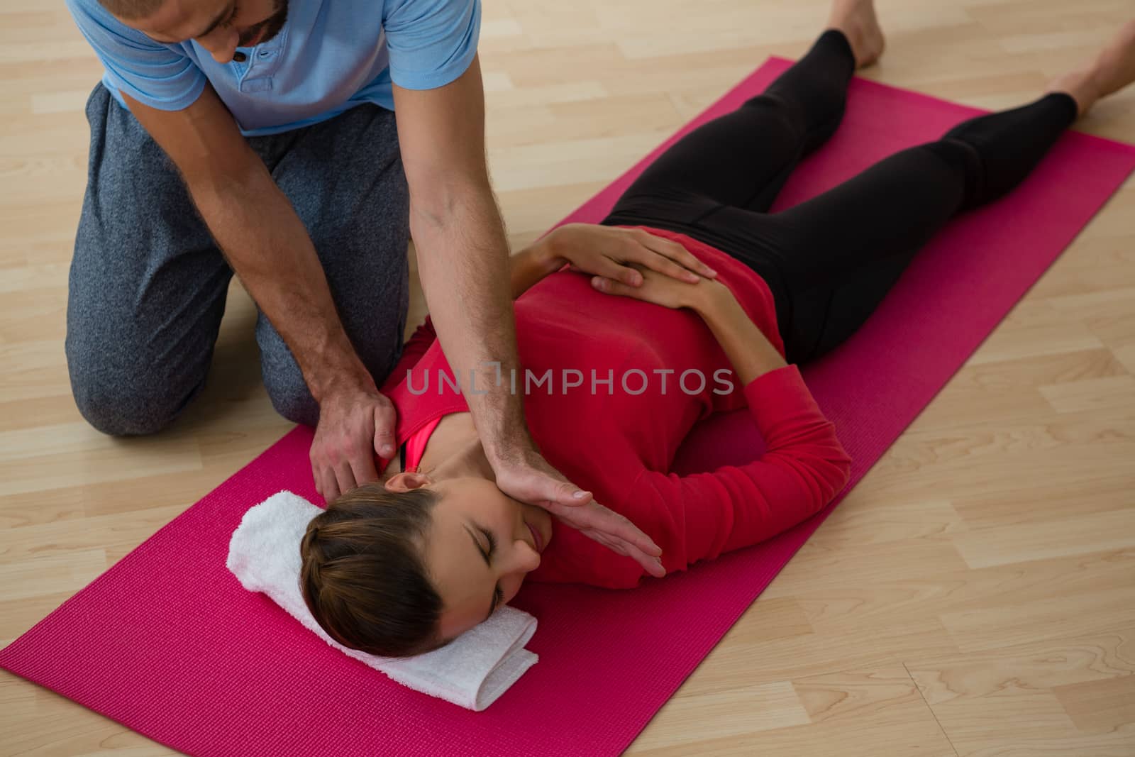 High angle view of instructor guiding student in exercising at yoga studio