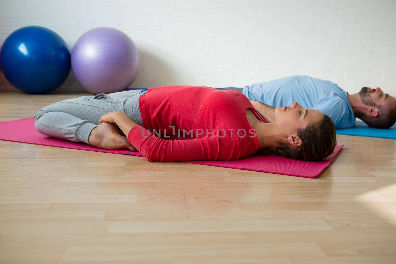 Instructor with student practicing reclined hero pose in studio by Wavebreakmedia