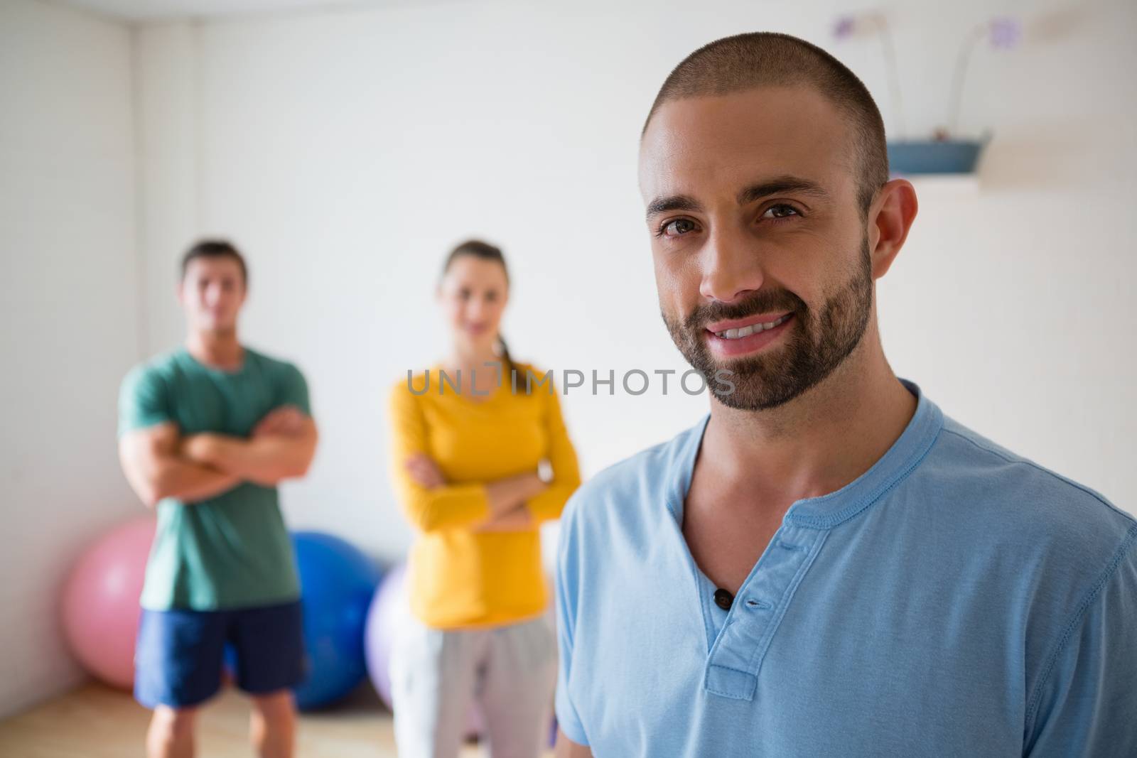 Portrait of confident yoga instructor with student in health club