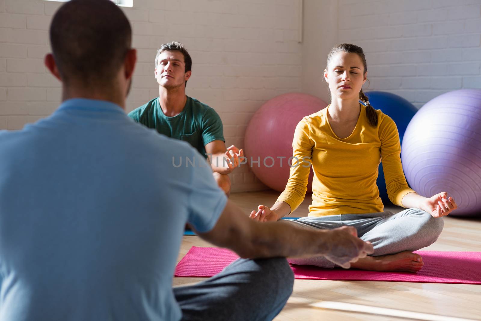 Yoga instructor guiding students in meditation at health club 