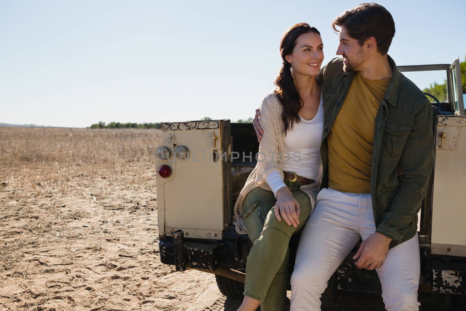 Romantic young couple sitting in off road vehicle on landscape
