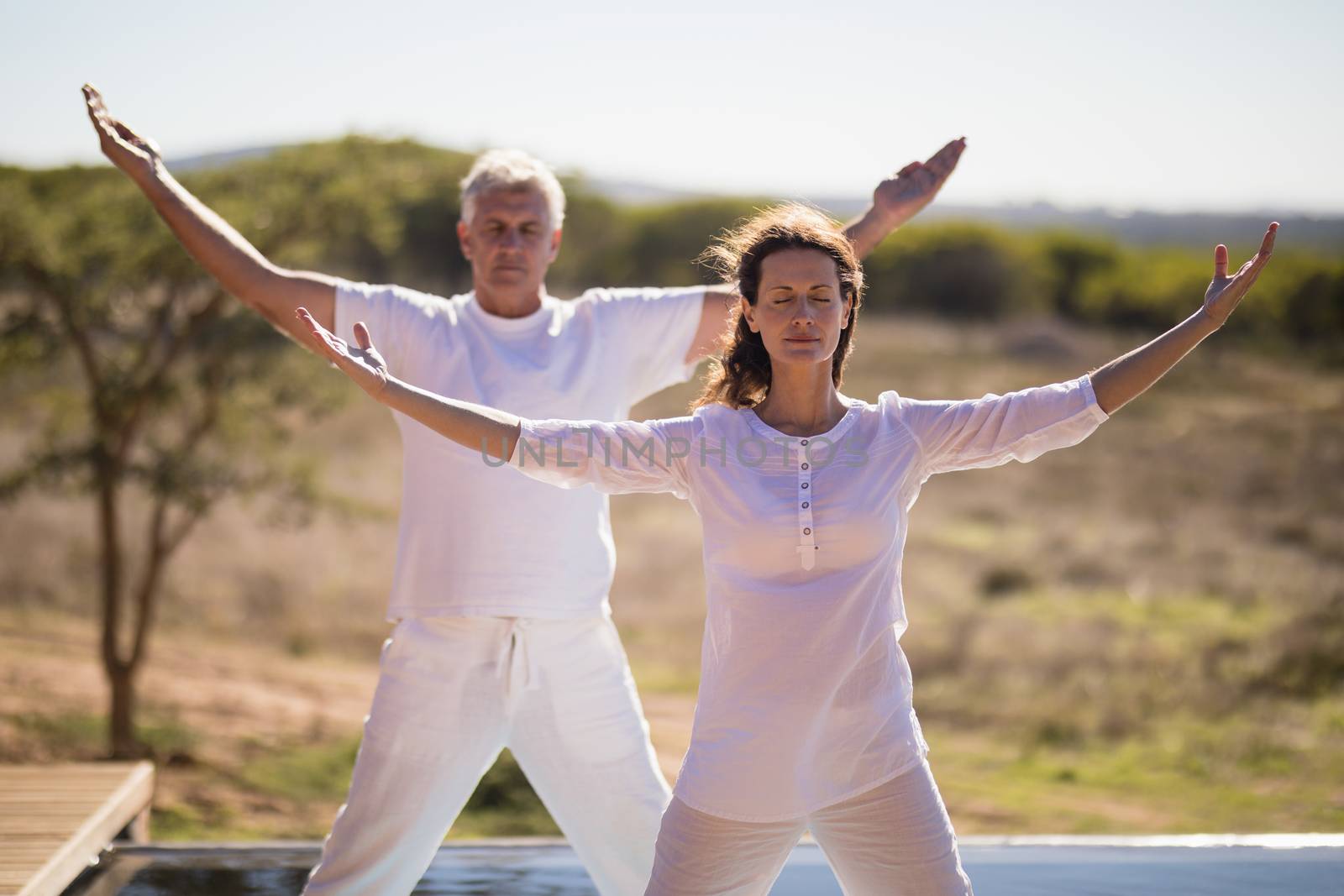 Couple practicing yoga on at poolside by Wavebreakmedia