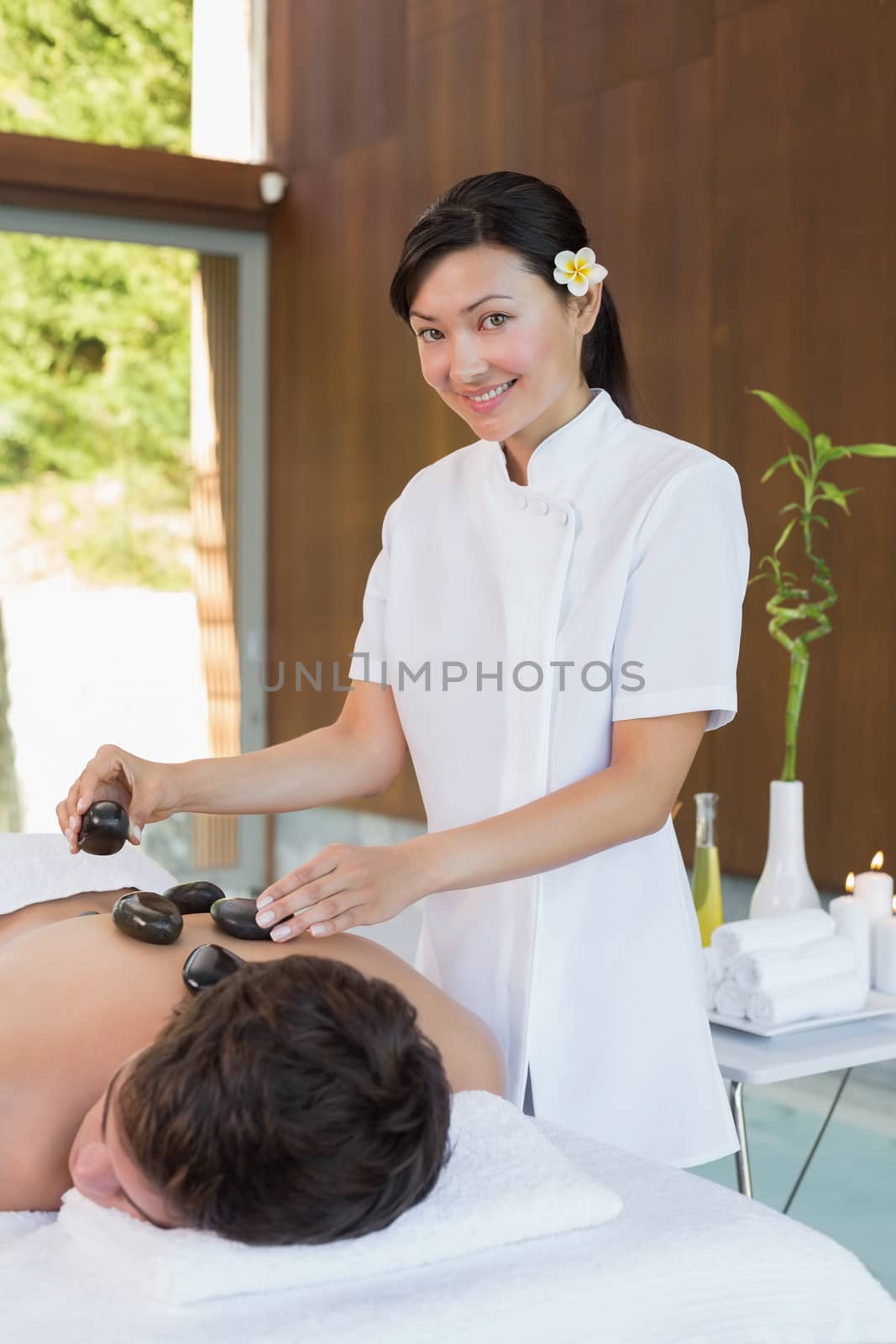 Handsome young man receiving stone massage at spa center