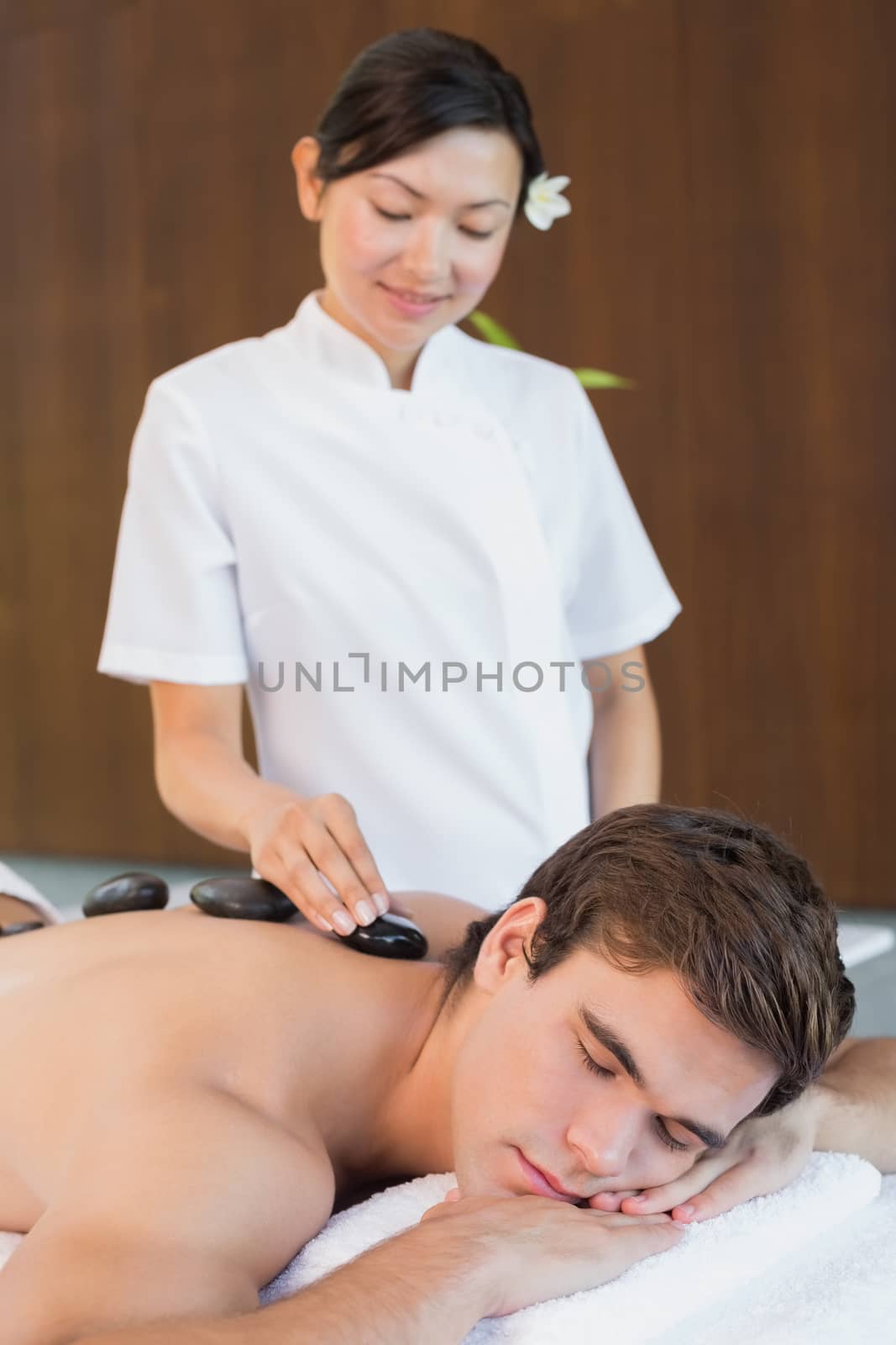 Handsome young man receiving stone massage at spa center