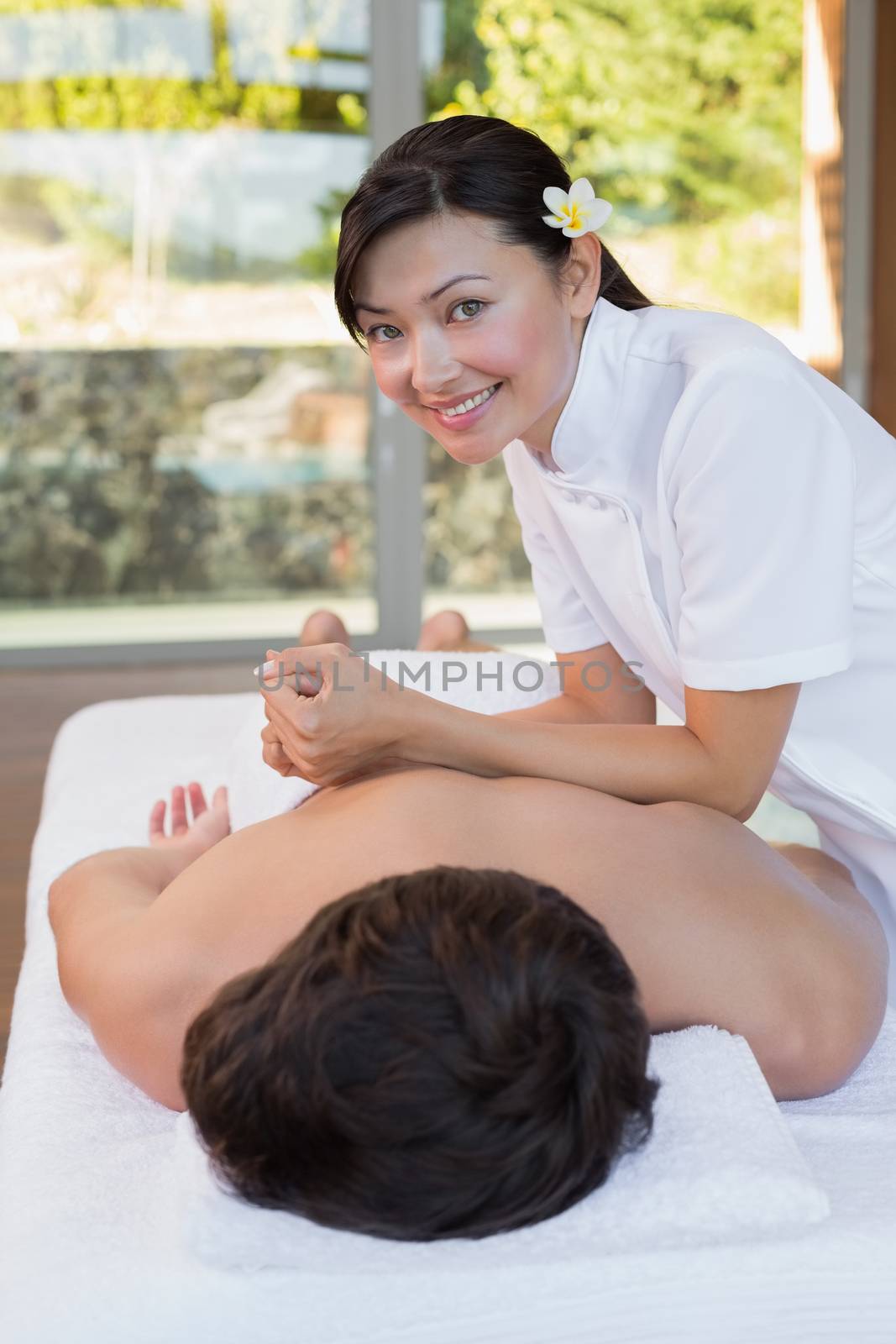 Female masseur massaging mans back at spa center by Wavebreakmedia