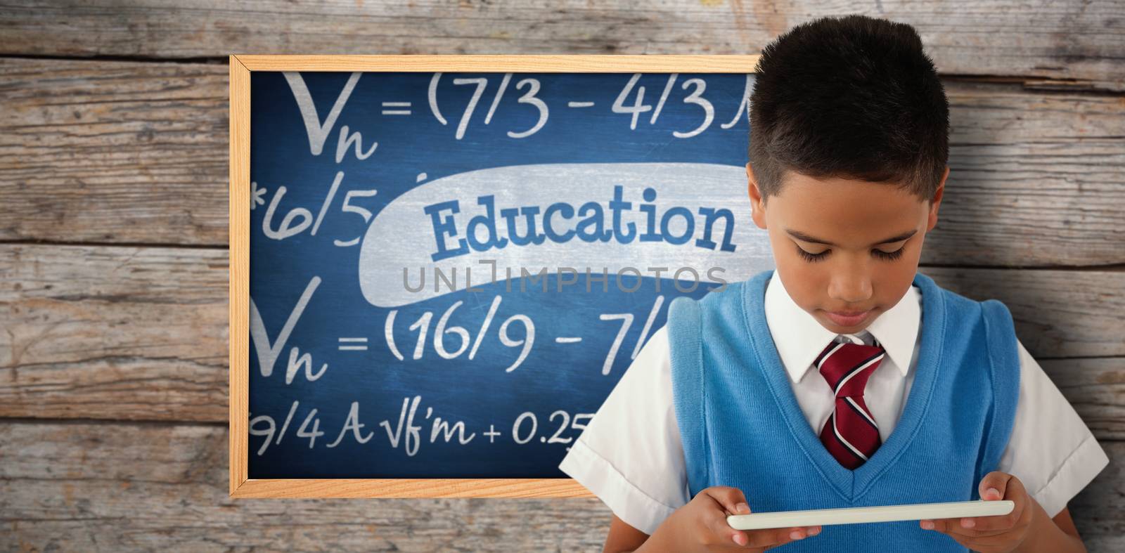 Schoolboy using digital tablet against education against blue chalkboard