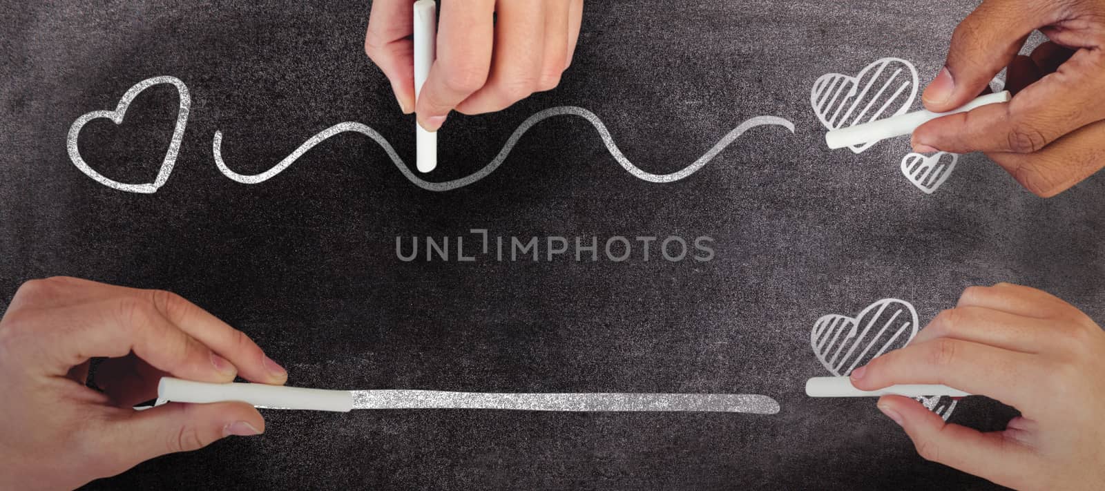 Cropped hands of people holding chalks against black background