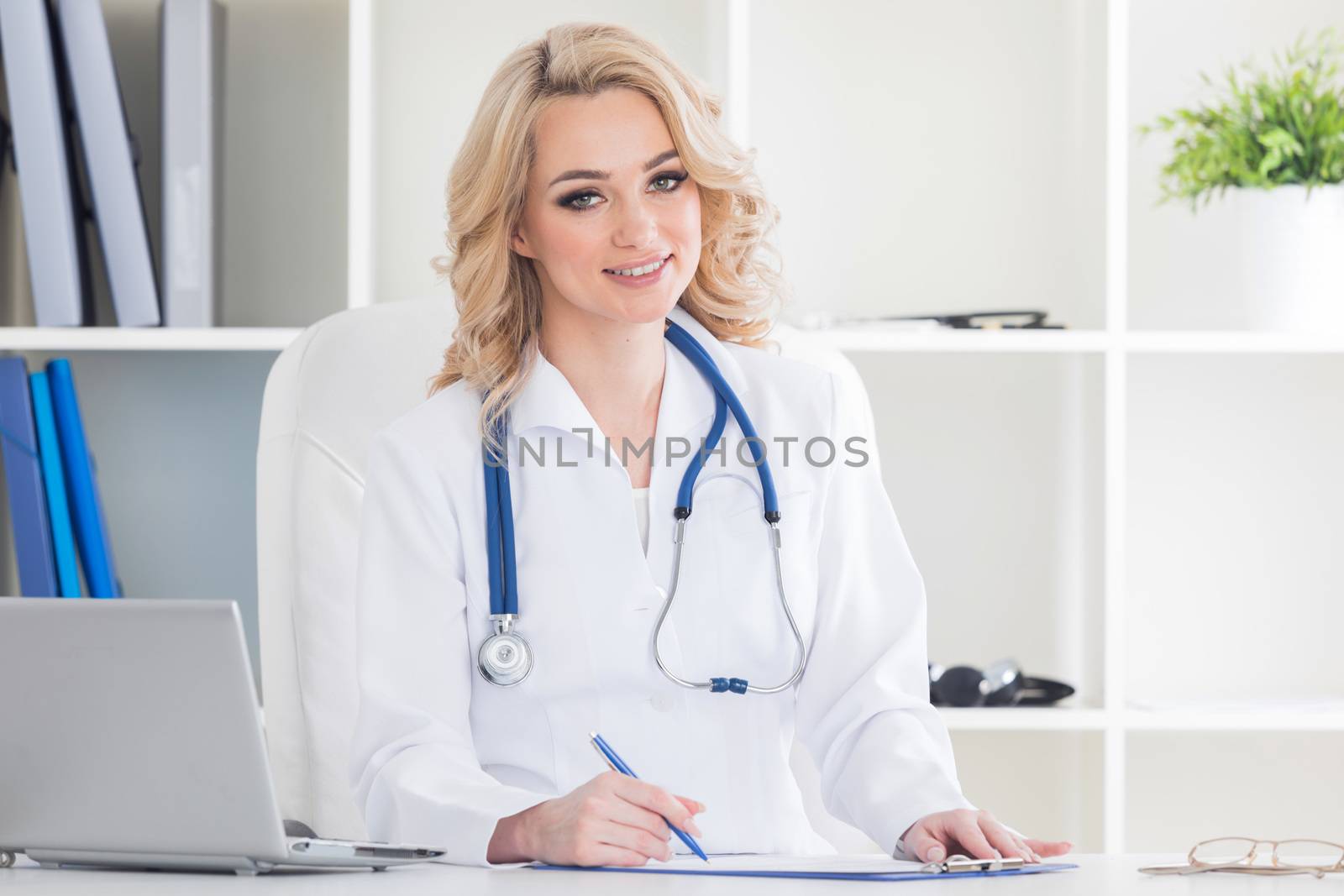 Young therapeutis female doctor writing prescription at desk in hospital office