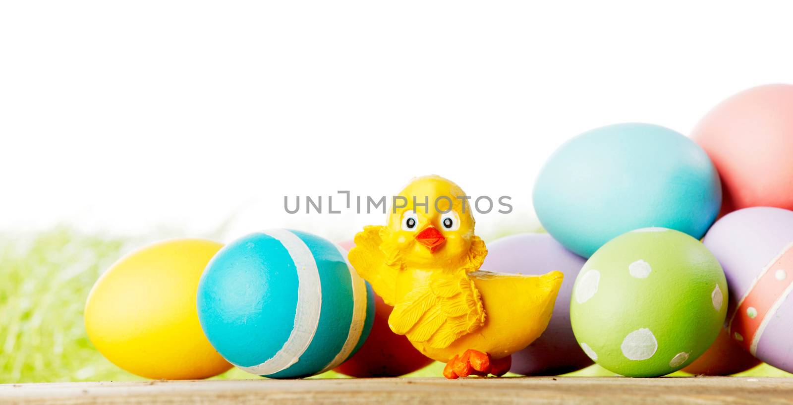 Easter composition with eggs and toy chick on green meadow isolated on white background