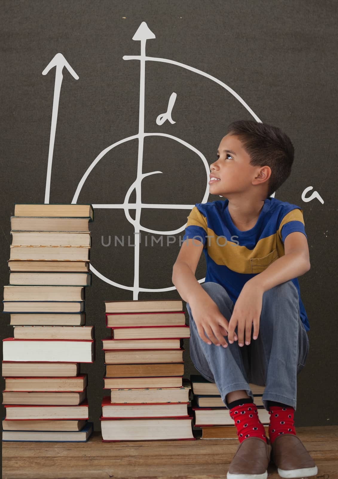 Digital composite of Student boy on a table looking up against grey blackboard with school and education graphic