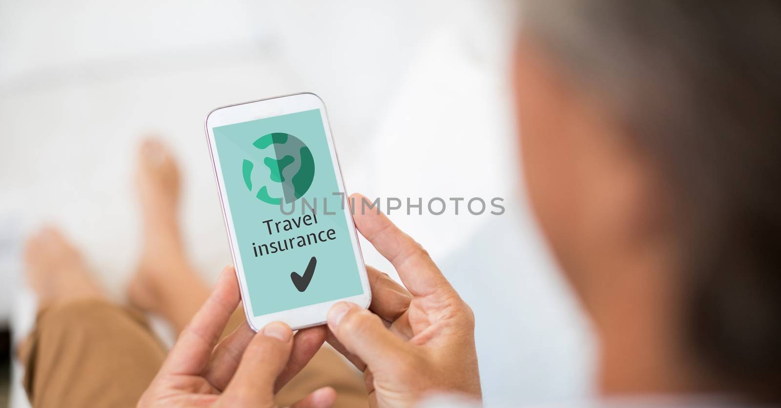 Man holding a phone with travel insurance concept on screen by Wavebreakmedia