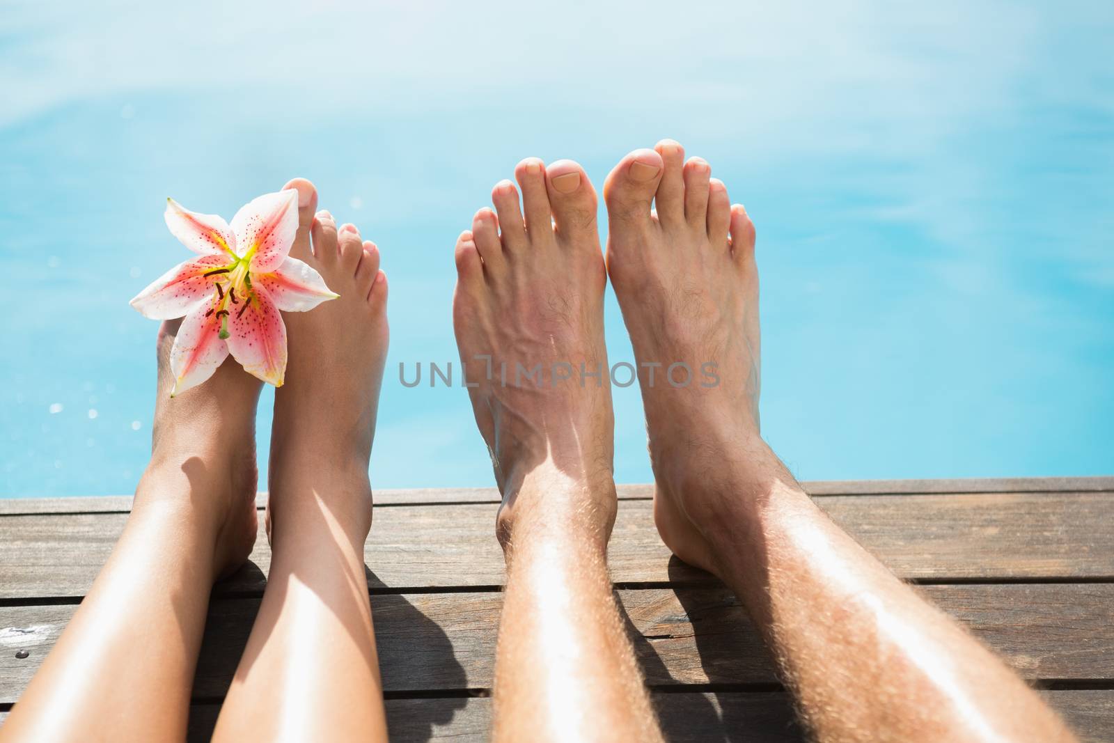Couple feet against swimming pool on a sunny day by Wavebreakmedia