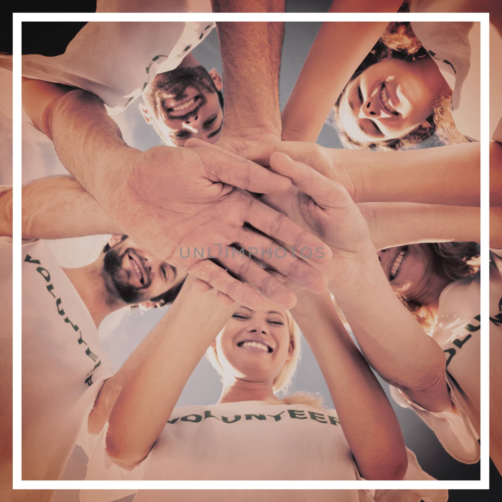 Low angle view of happy volunteers with hands together against blue sky